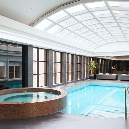 Stamford Plaza Melbourne Hotel Ngoại thất bức ảnh The photo shows an indoor swimming pool area. The pool is rectangular and has clear blue water, surrounded by a sleek, modern design. On one side, there is a round hot tub made of dark stone. Large windows line the walls, allowing natural light to fi