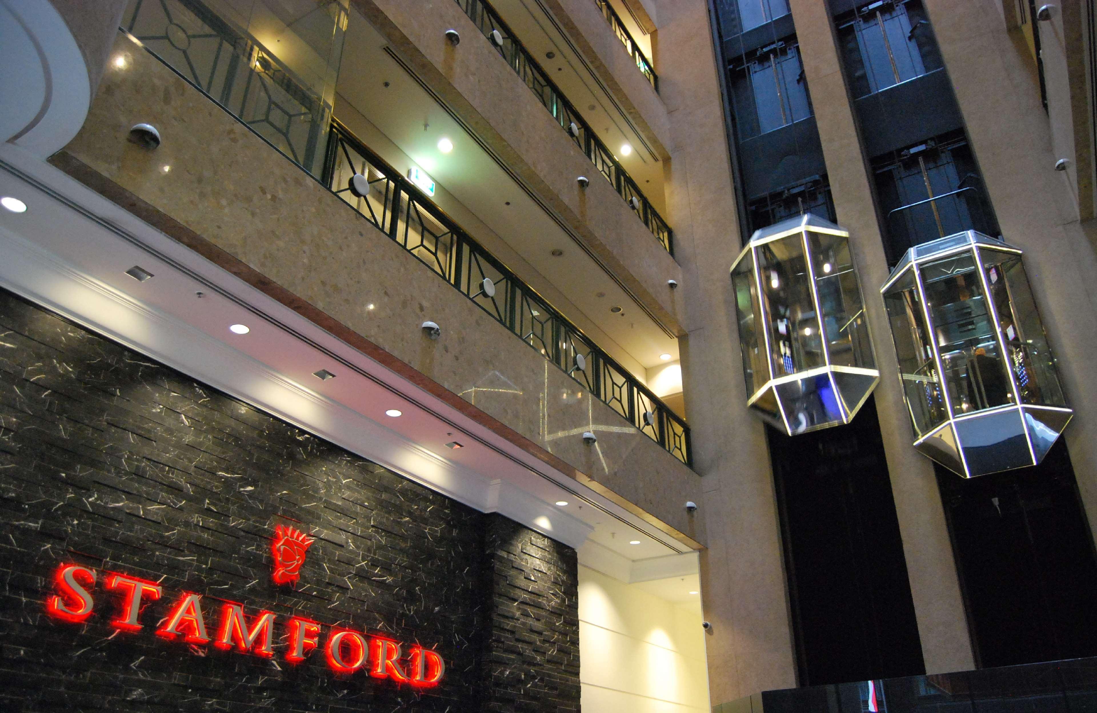 Stamford Plaza Melbourne Hotel Ngoại thất bức ảnh The photo shows the interior of a building, likely a hotel or commercial space. There is a prominent sign with the name "STAMFORD" in red lettering against a dark stone background. The building features several floors, visible from the photograph, wi