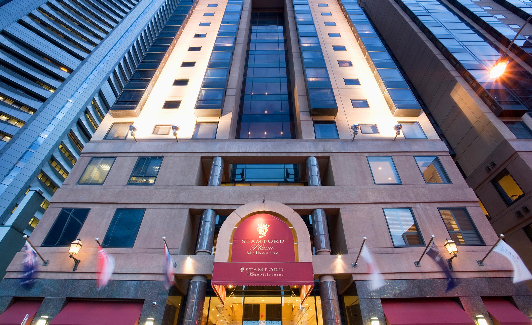 Stamford Plaza Melbourne Hotel Ngoại thất bức ảnh The photo shows the entrance of a modern hotel building. The architecture features a tall structure with glass and stone elements. The hotel's name is visible above the entrance, which is framed by an arch, and the facade includes multiple levels wit