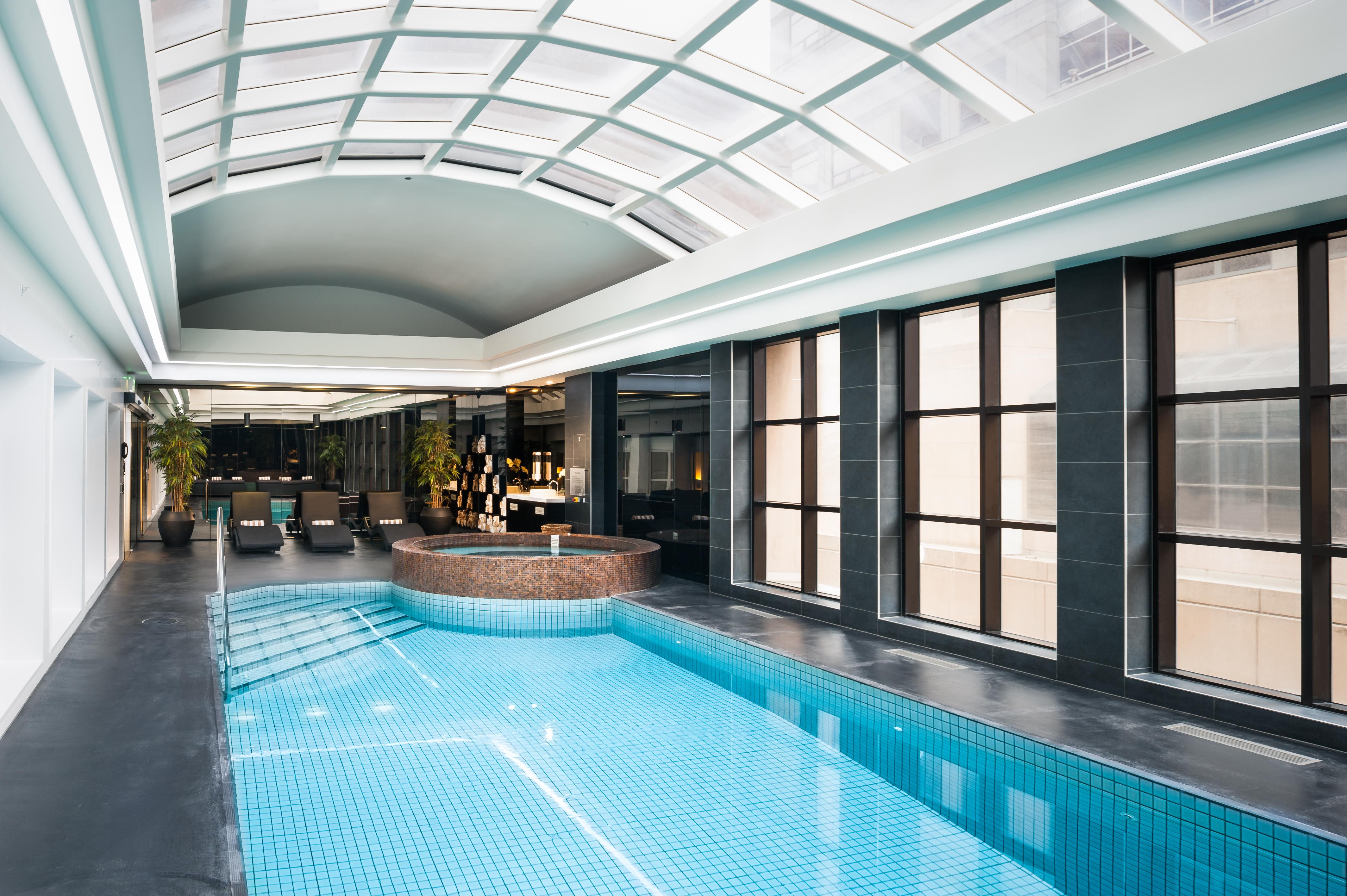 Stamford Plaza Melbourne Hotel Ngoại thất bức ảnh The photo shows an indoor swimming pool area with a modern and sleek design. The pool is rectangular and features bright blue tiles. Above the pool, there's a large, transparent glass ceiling that allows natural light to flood the space. Surrounding 