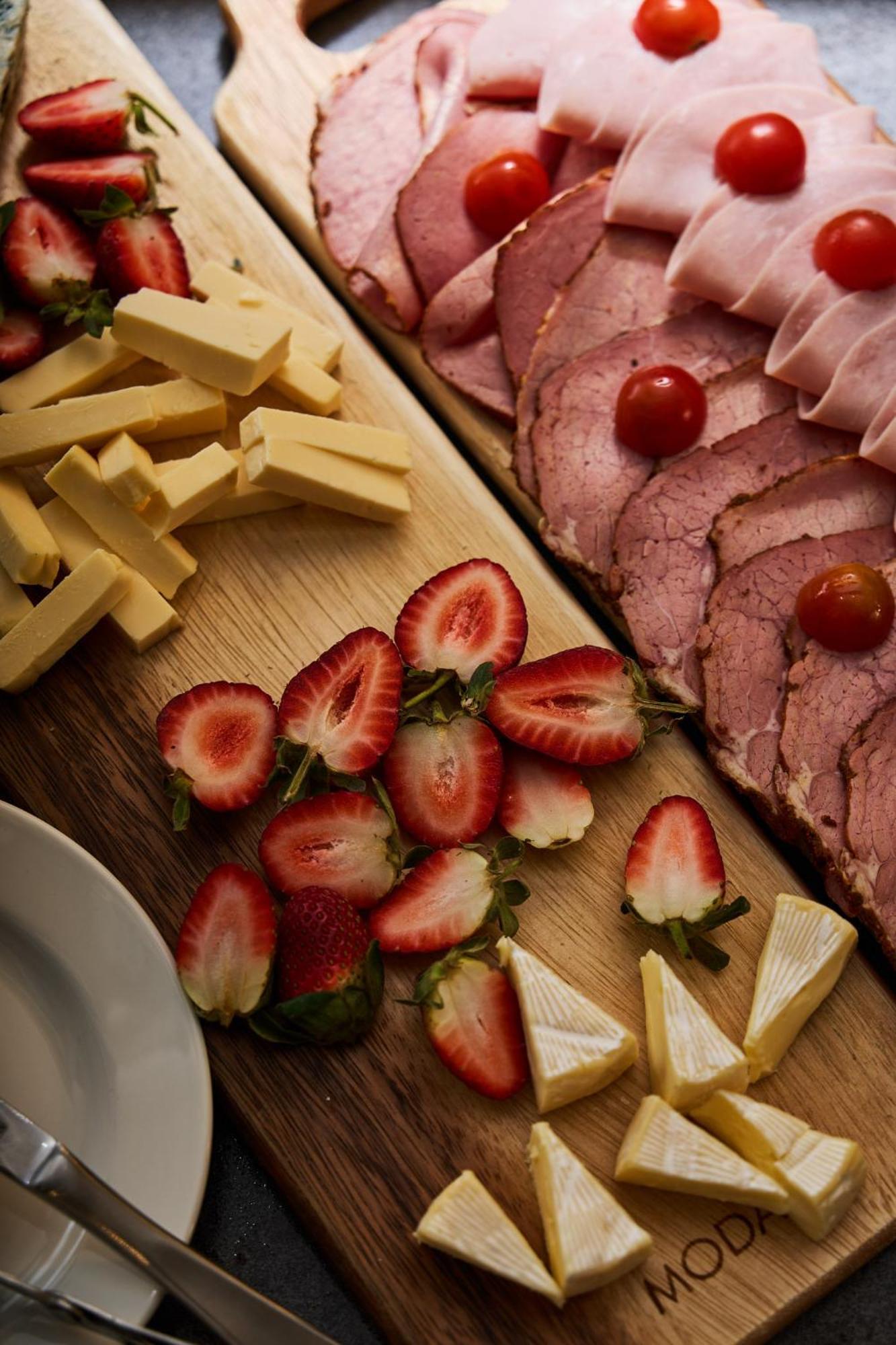 Stamford Plaza Melbourne Hotel Ngoại thất bức ảnh The photo displays an assortment of food items arranged on a wooden surface. There are slices of various meats, including ham, alongside round cherry tomatoes. Next to the meat, there are several pieces of yellow cheese cut into sticks. Additionally,