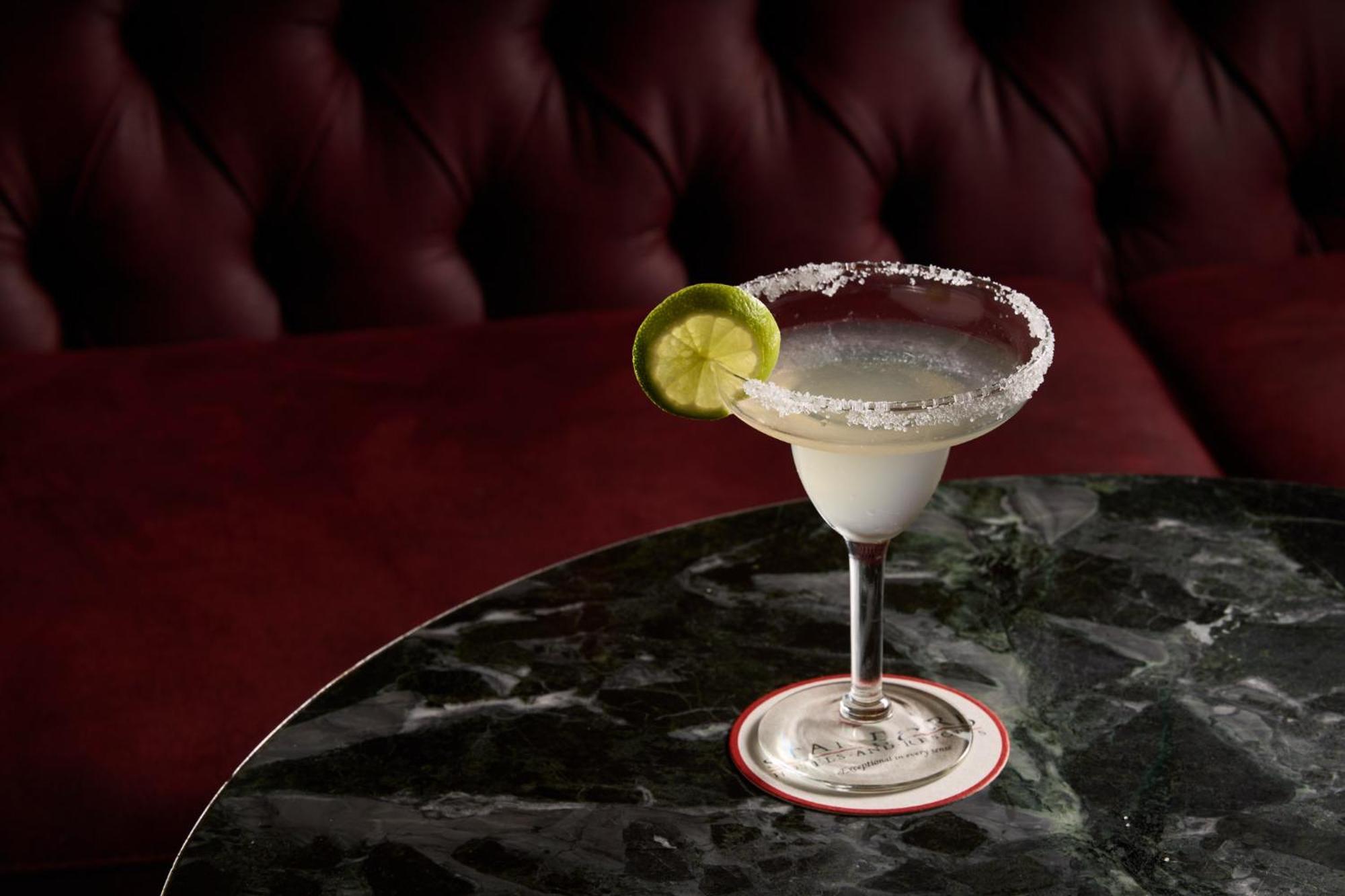 Stamford Plaza Melbourne Hotel Ngoại thất bức ảnh The photo shows a beautifully presented margarita cocktail served in a classic margarita glass. The drink is clear with a salt rim around the edge, and adorned with a slice of lime. The glass is placed on a dark green marble table, contrasting with a