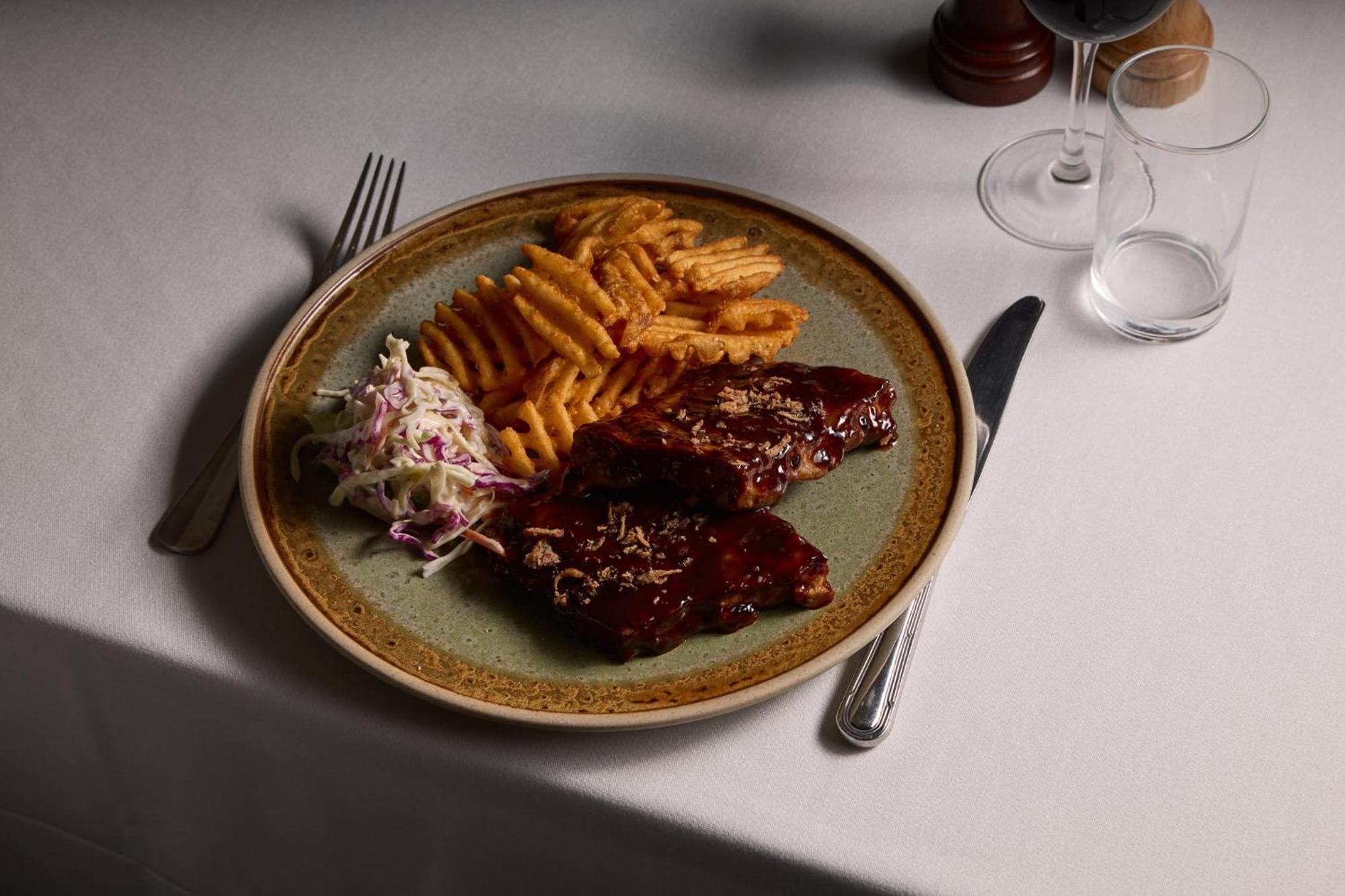 Stamford Plaza Melbourne Hotel Ngoại thất bức ảnh The photo displays a plate of food featuring two pieces of steak that appear to be glazed with a rich sauce. Alongside the steak, there are crinkle-cut fries arranged neatly on one side of the plate. Additionally, there's a small serving of coleslaw,
