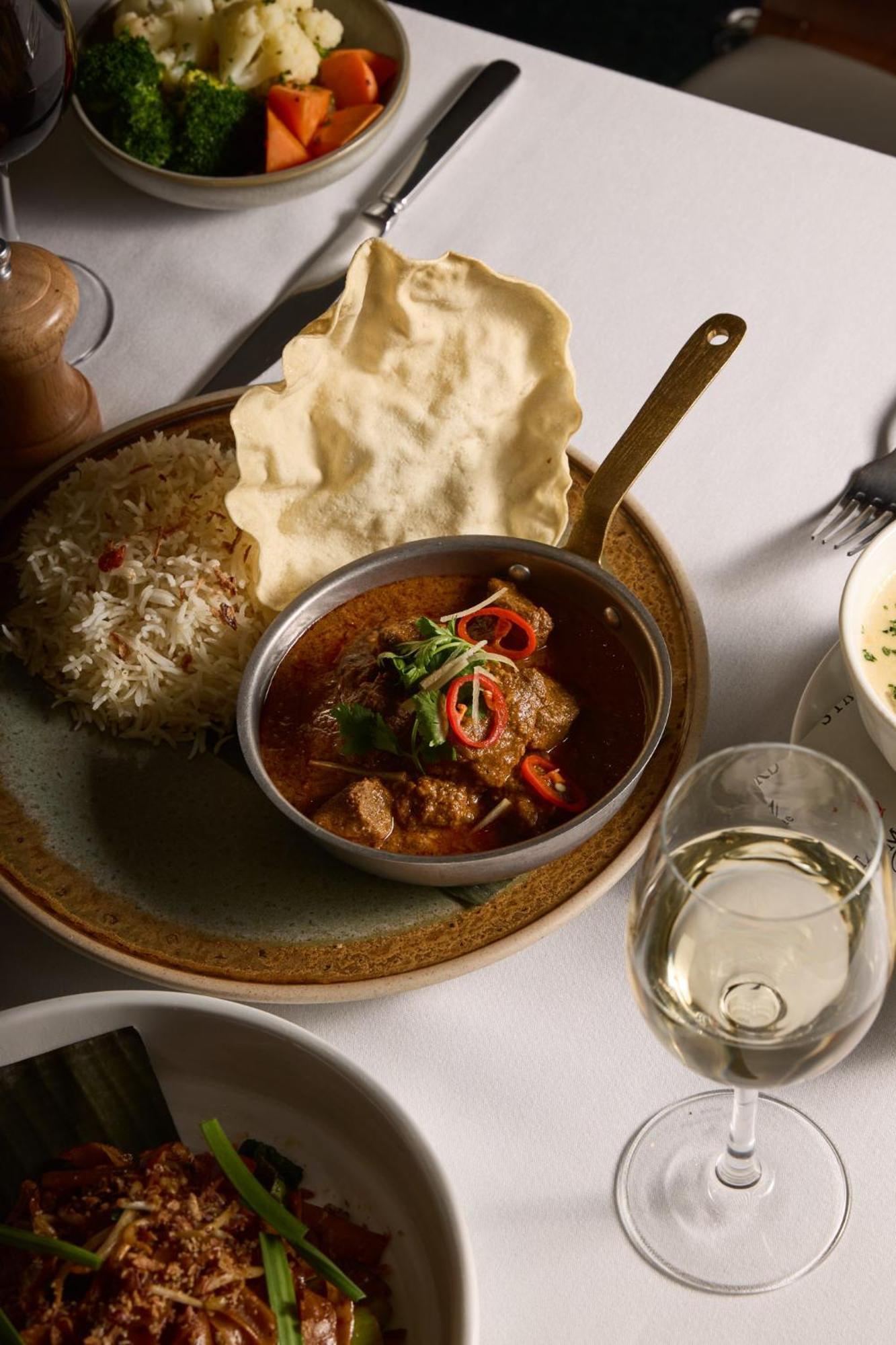 Stamford Plaza Melbourne Hotel Ngoại thất bức ảnh The photo features a plated meal that includes a serving of meat curry in a small round dish. The curry is garnished with herbs and slices of chili. Accompanying the curry, there is a mound of fluffy rice, and a piece of crispy flatbread (poppadom) r