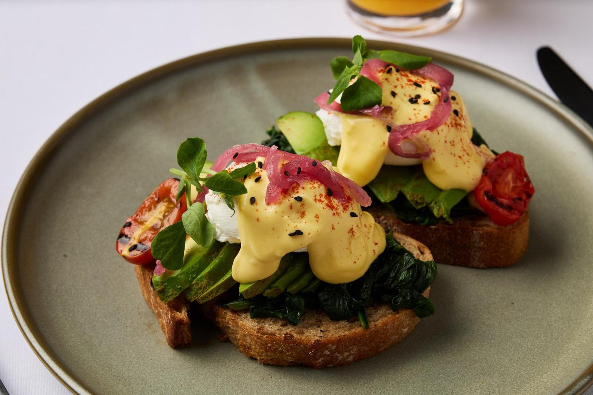 Stamford Plaza Melbourne Hotel Ngoại thất bức ảnh The photo shows a plate featuring two pieces of toasted bread topped with a variety of ingredients. Each slice is layered with sautéed spinach and other greens, along with slices of cucumber and cherry tomatoes. The dish is finished with poached eggs